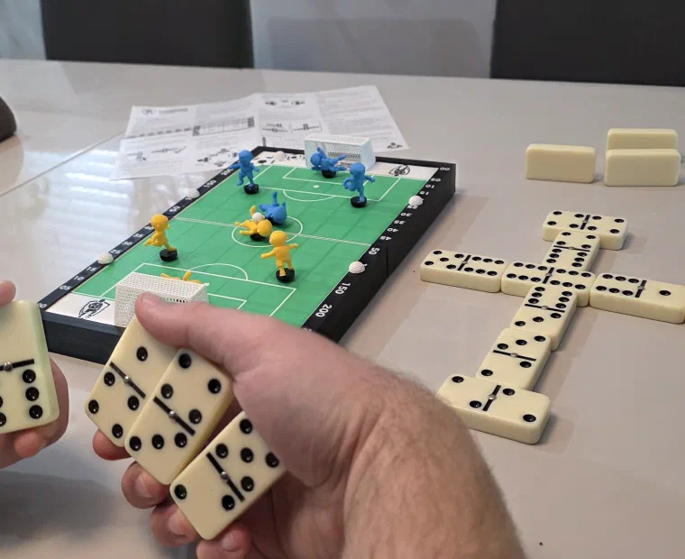 Friends playing Domino Futebol Clube at home with domino tiles on the table